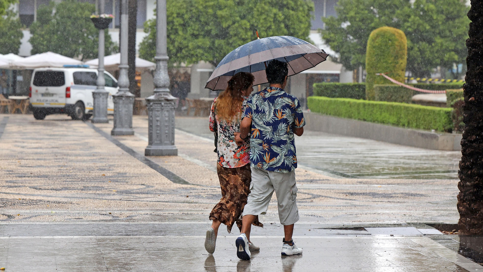 Una pareja, paseando con paragüas por la Plaza del Arenal.