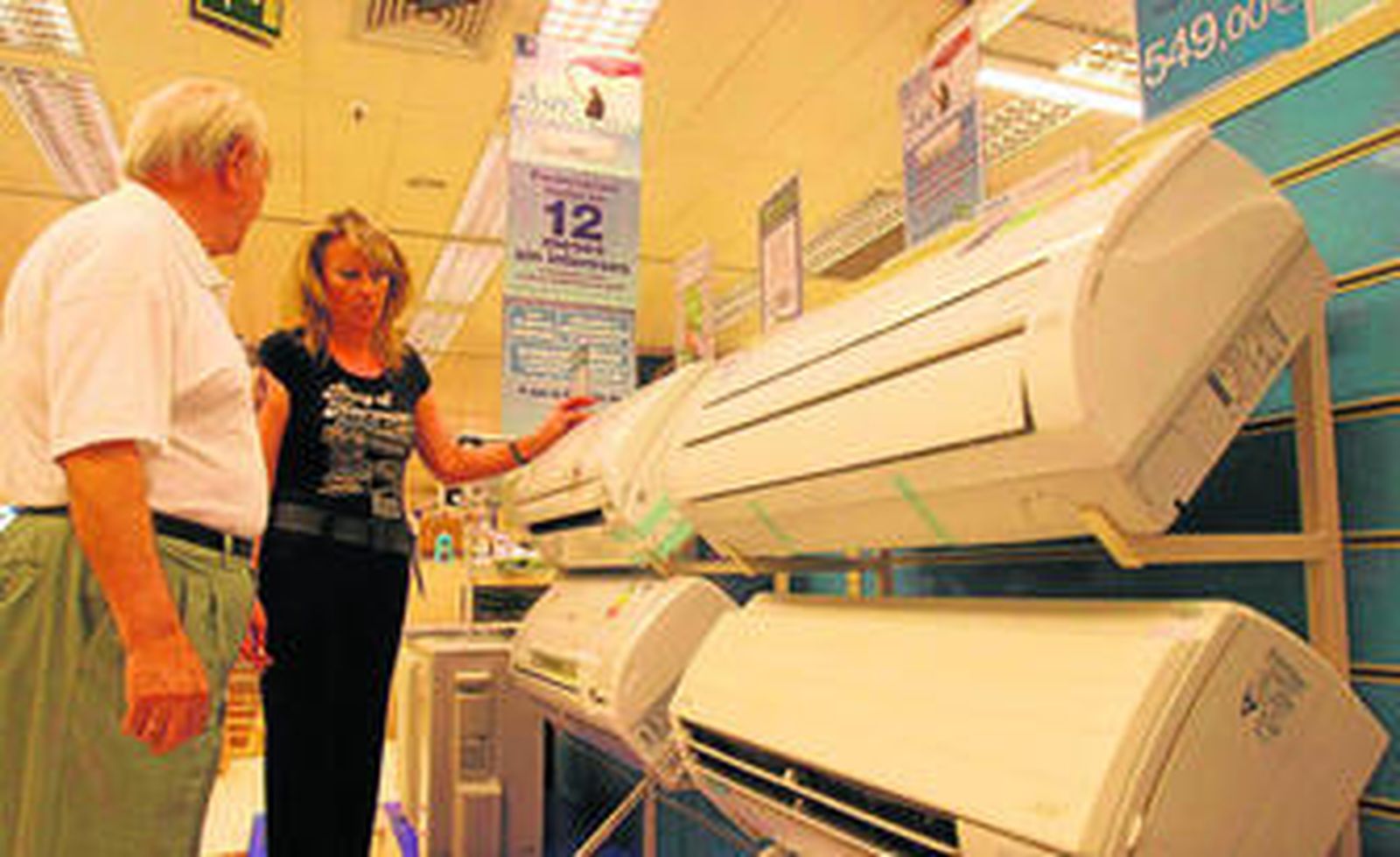 Clientes eligiendo aparatos de aire acondicionado en la exposición de un comercio.
