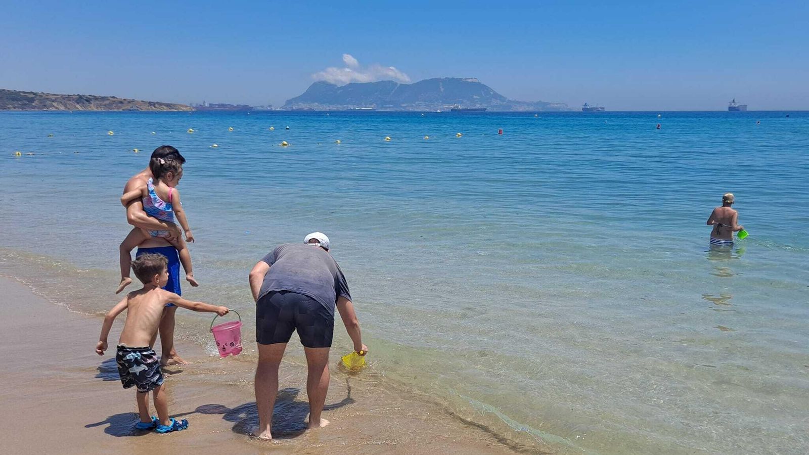 Paseantes recogiendo medusas en la orilla