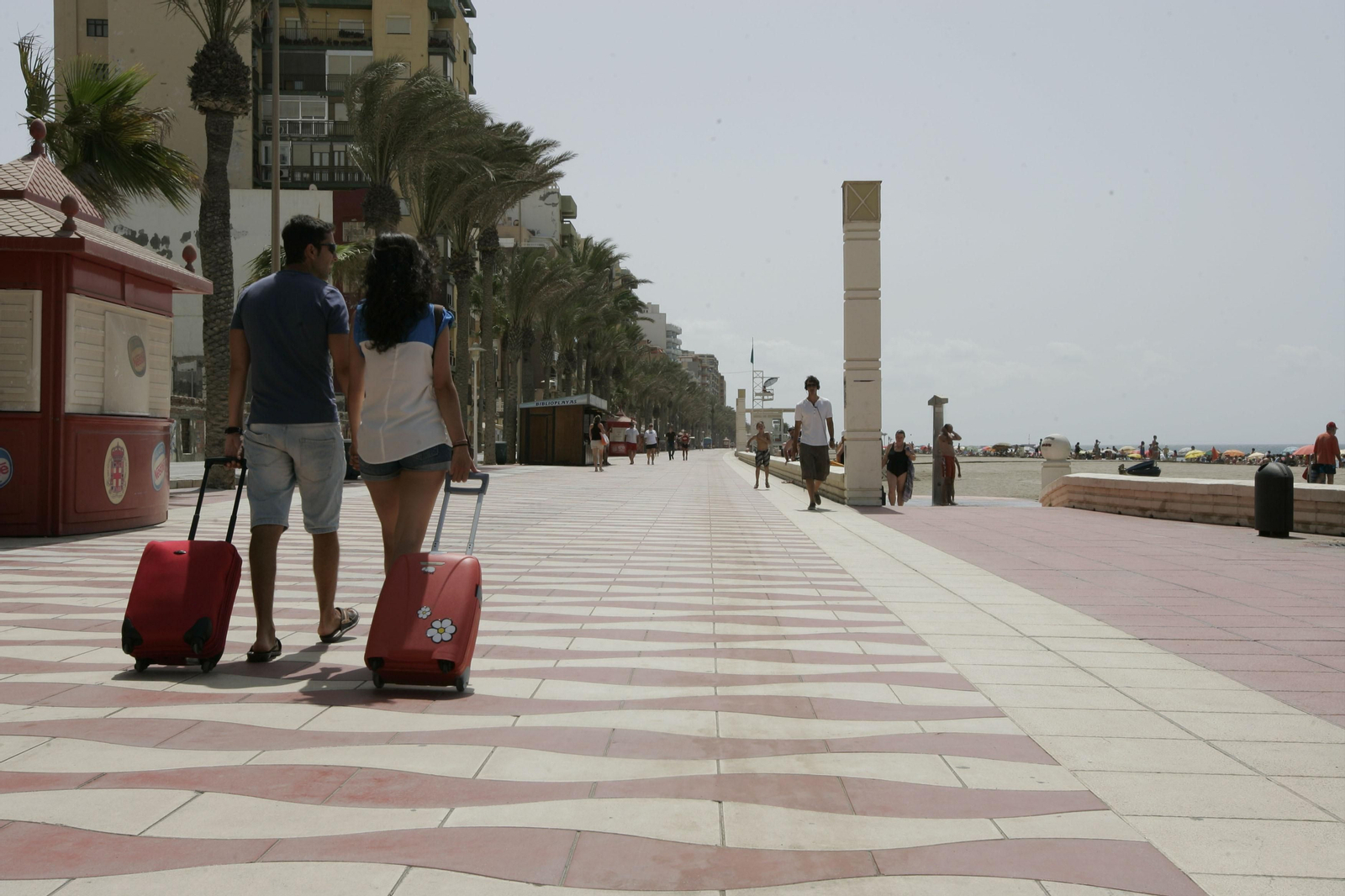 Turistas con maletas por el Paseo Marítimo.