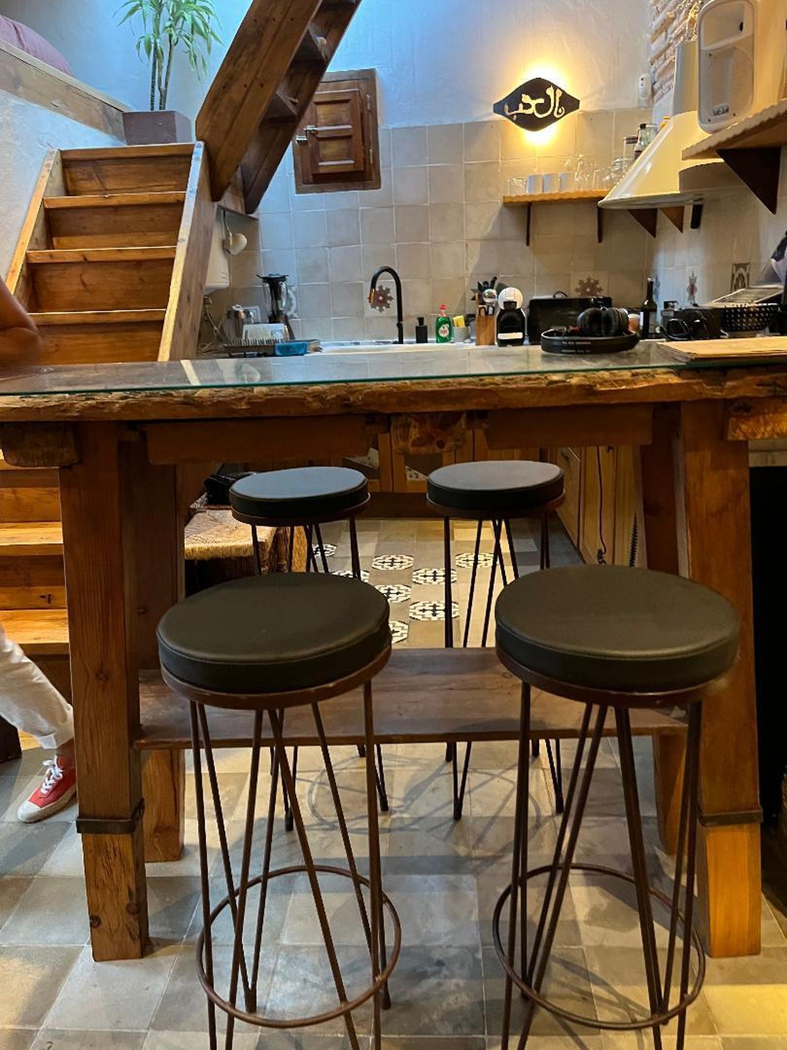 Un antiguo trillo de madera cubierto con un cristal se utiliza como mesa de comedor.