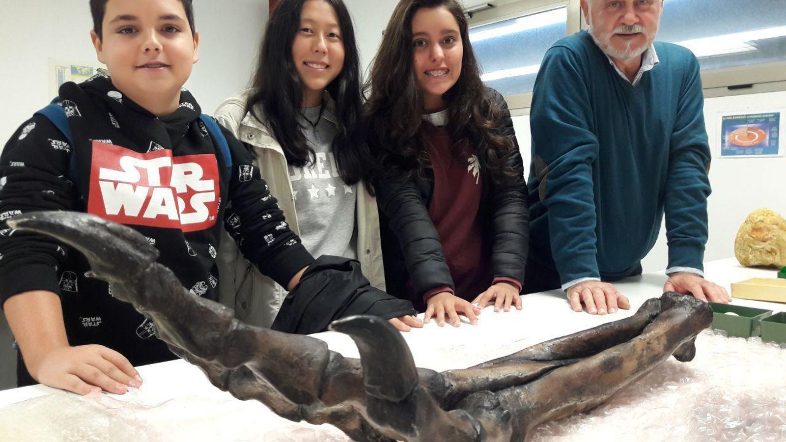 Alumnos y profesor con los restos de un dinosaurio
