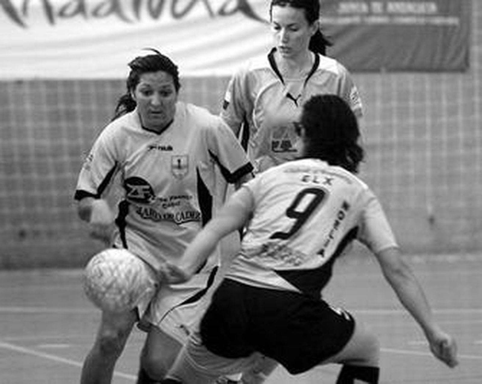 Montse observa el balón presionada por dos rivales.