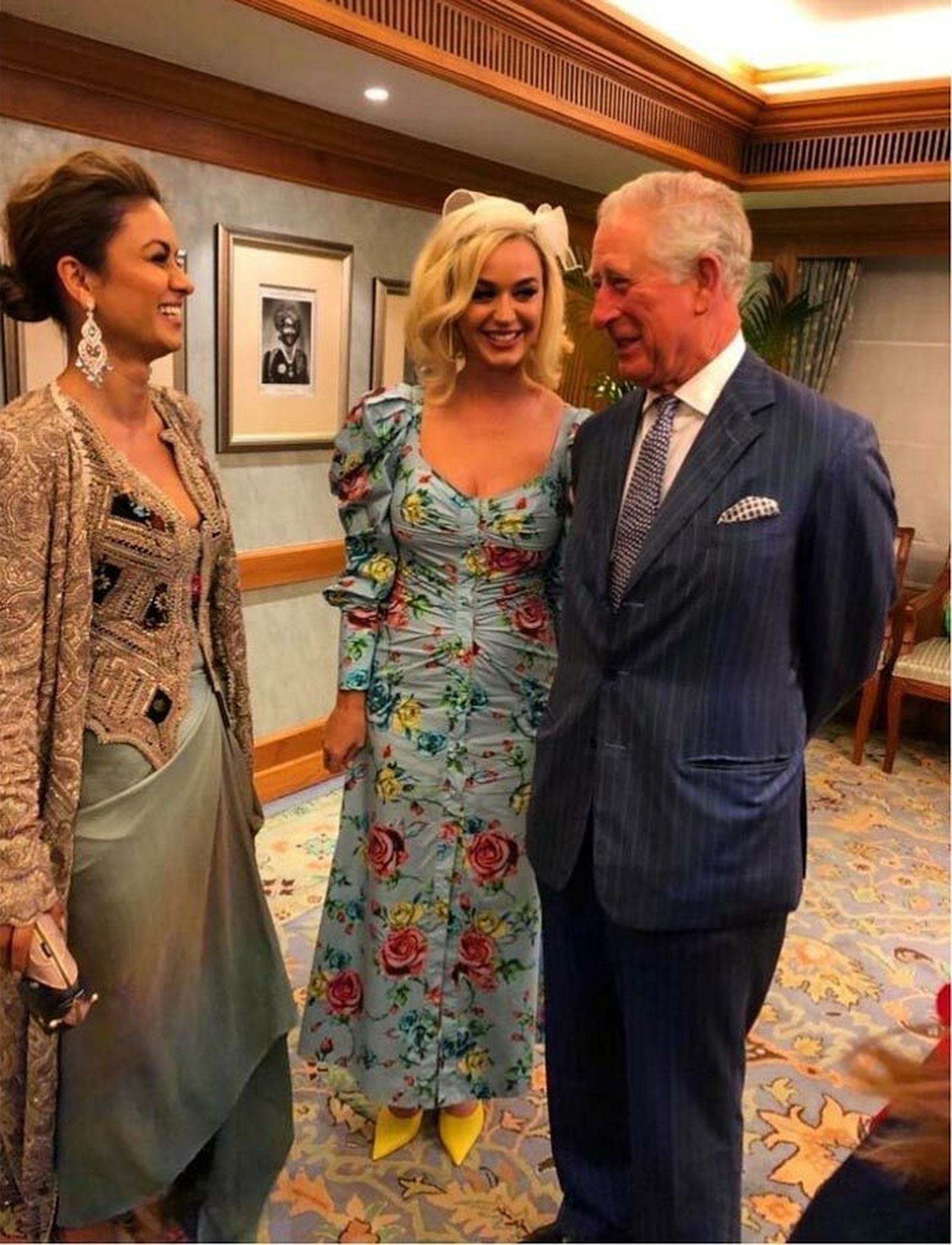 El príncipe Carlos sonríe en presencia de la cantante Katy Perry y otra artista.