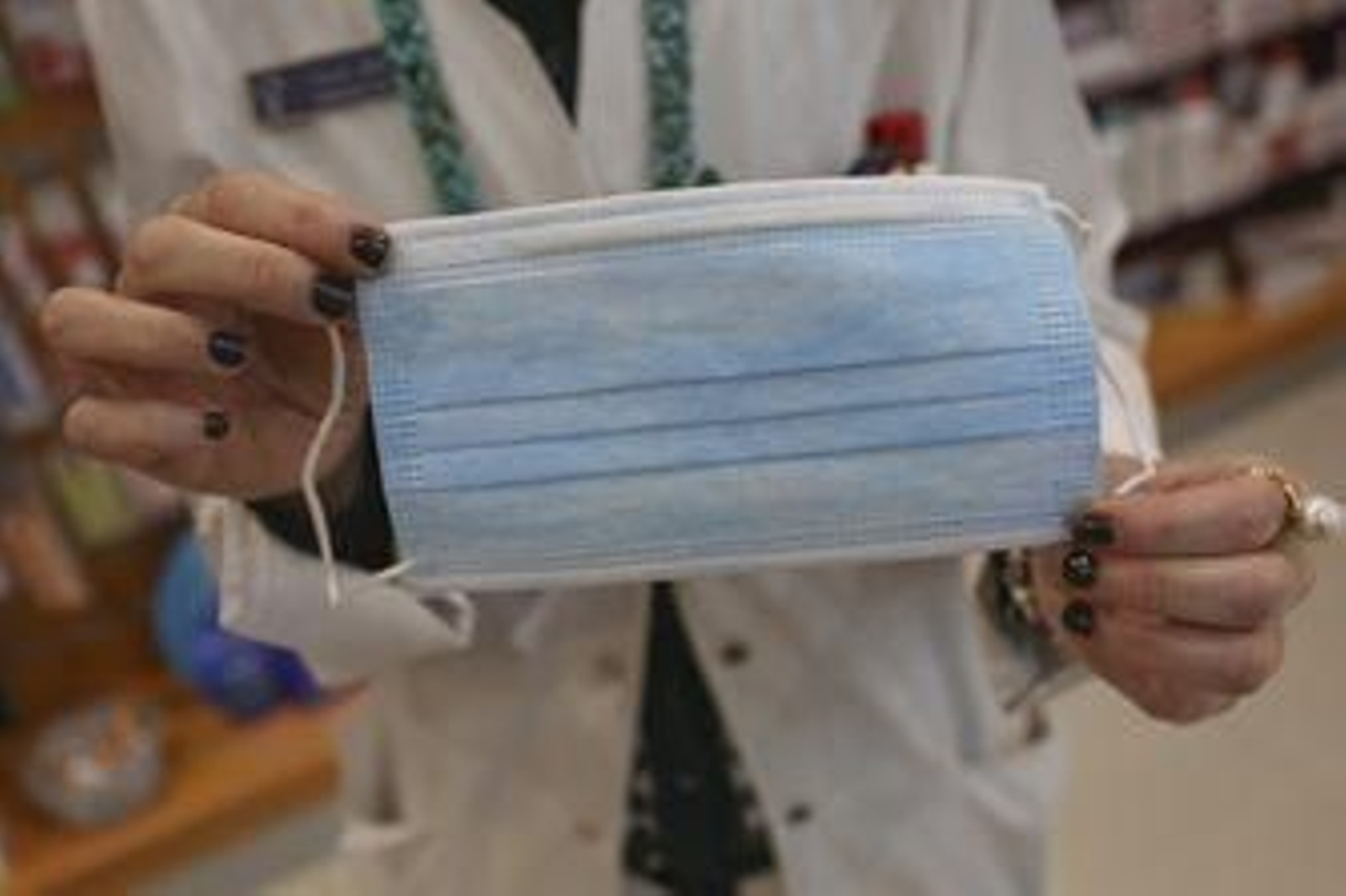 Una sanitaria sostiene una mascarilla.