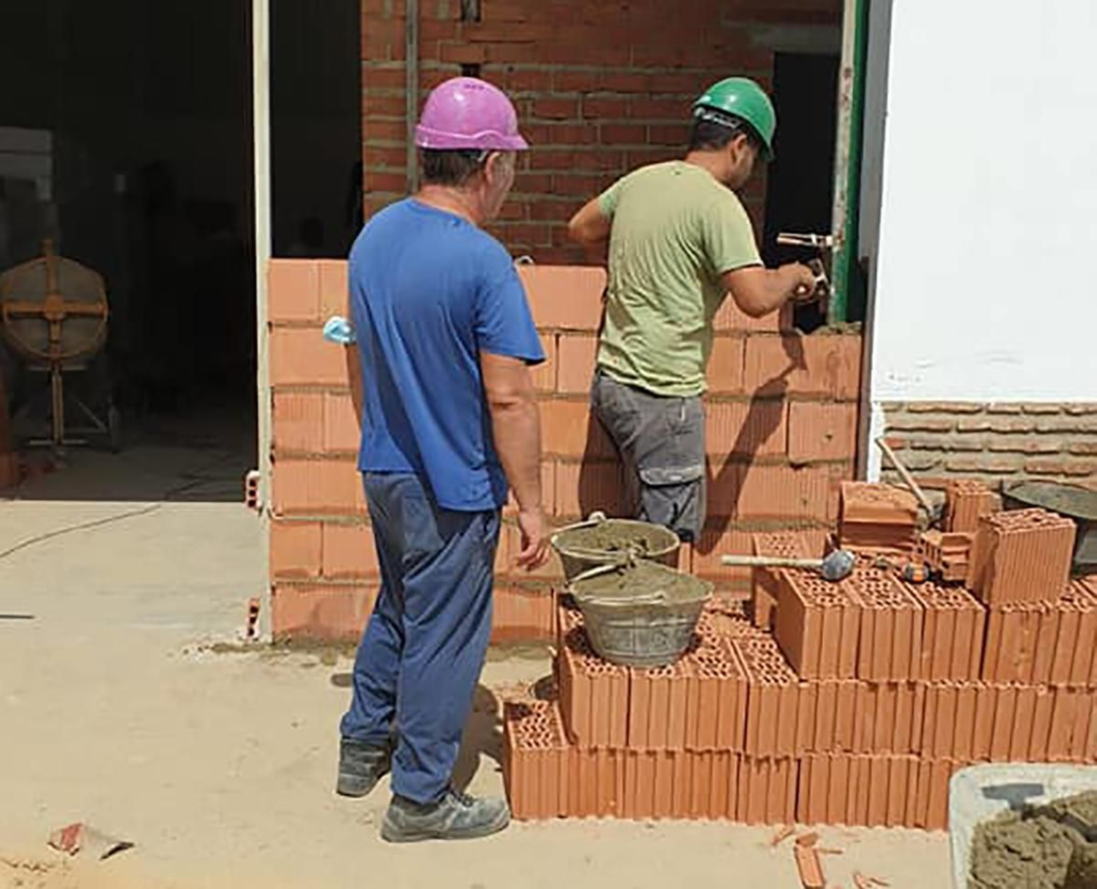 Dos obreros ponen los primeros ladrillos del nuevo albergue para inmigrantes