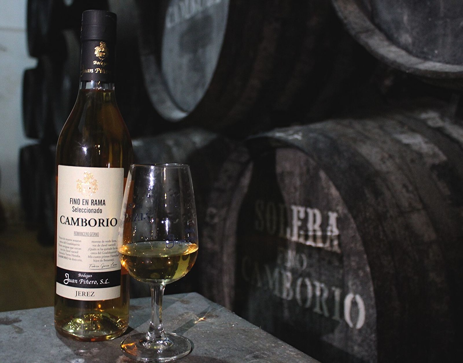Botella y copa del Fino Camborio en Rama Seleccionado junto a sus soleras en las bodegas Juan Piñero de Sanlúcar.