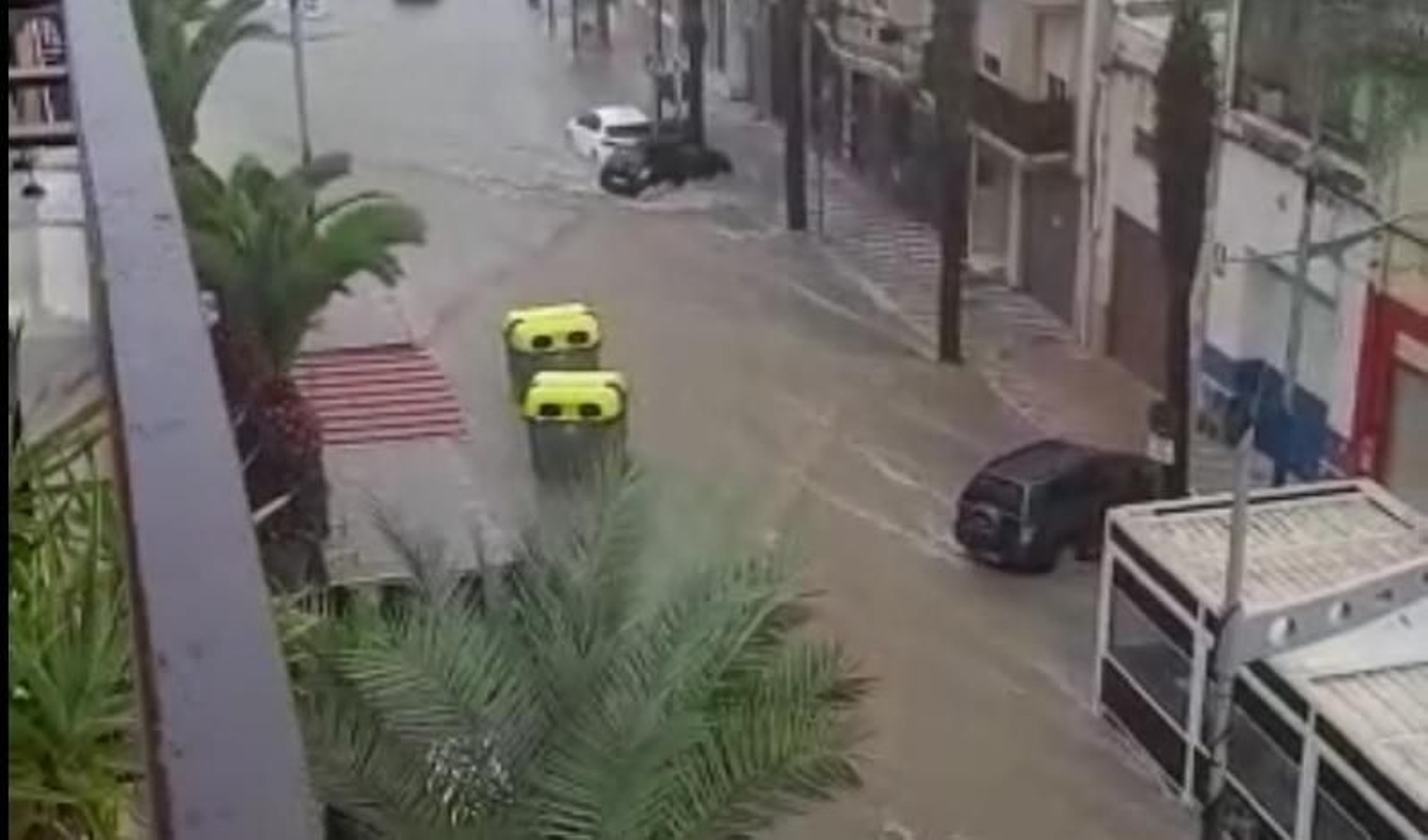 El agua arrastra dos contenedores en una avenida de Olula del Río.