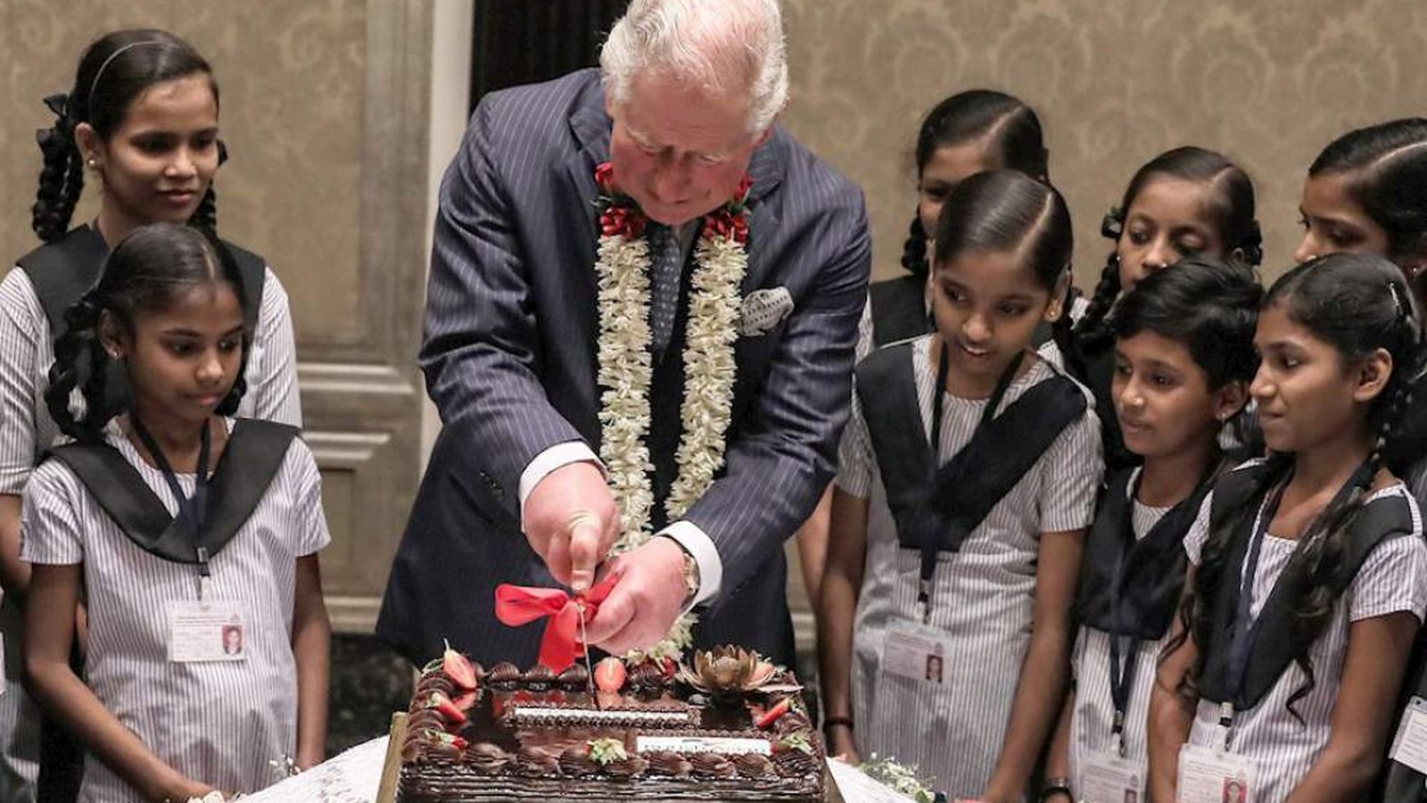 El príncipe Carlos corta su tarta en la India rodeado de niñas del país.