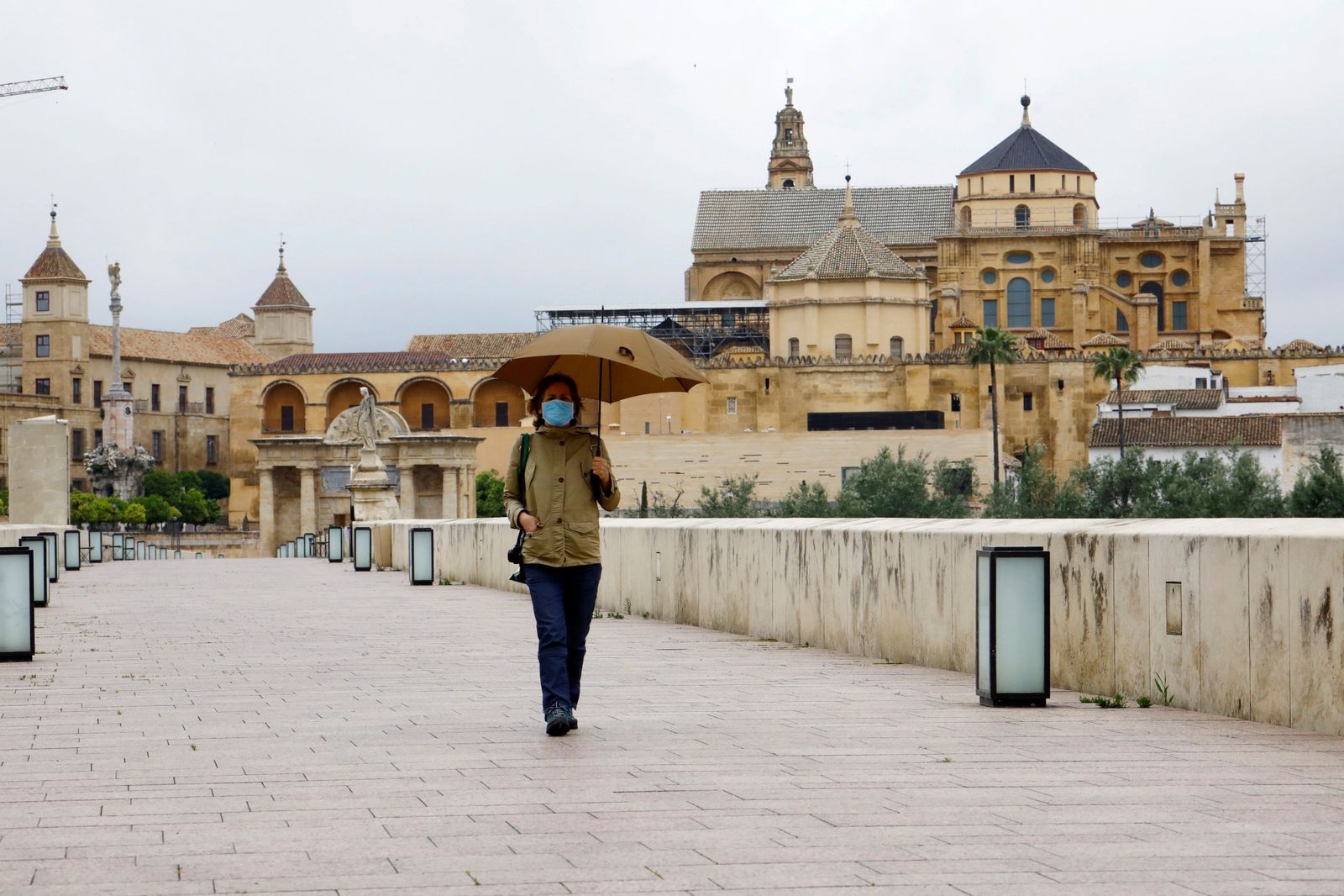 Una mujer pasea bajo un paraguas por el Puente Romano de Córdoba.