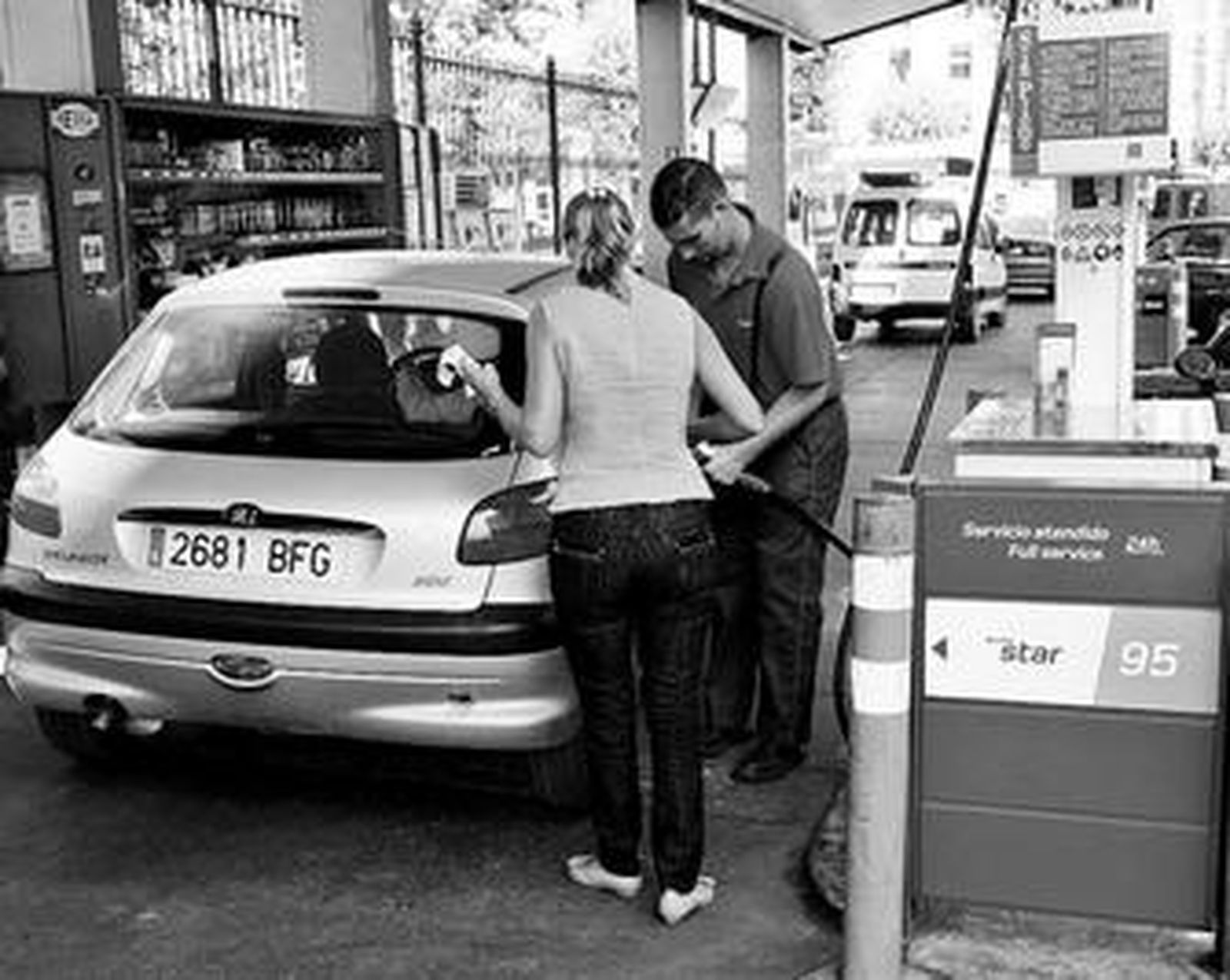 El dependiente de una gasolinera surte de carburante a un vehículo.