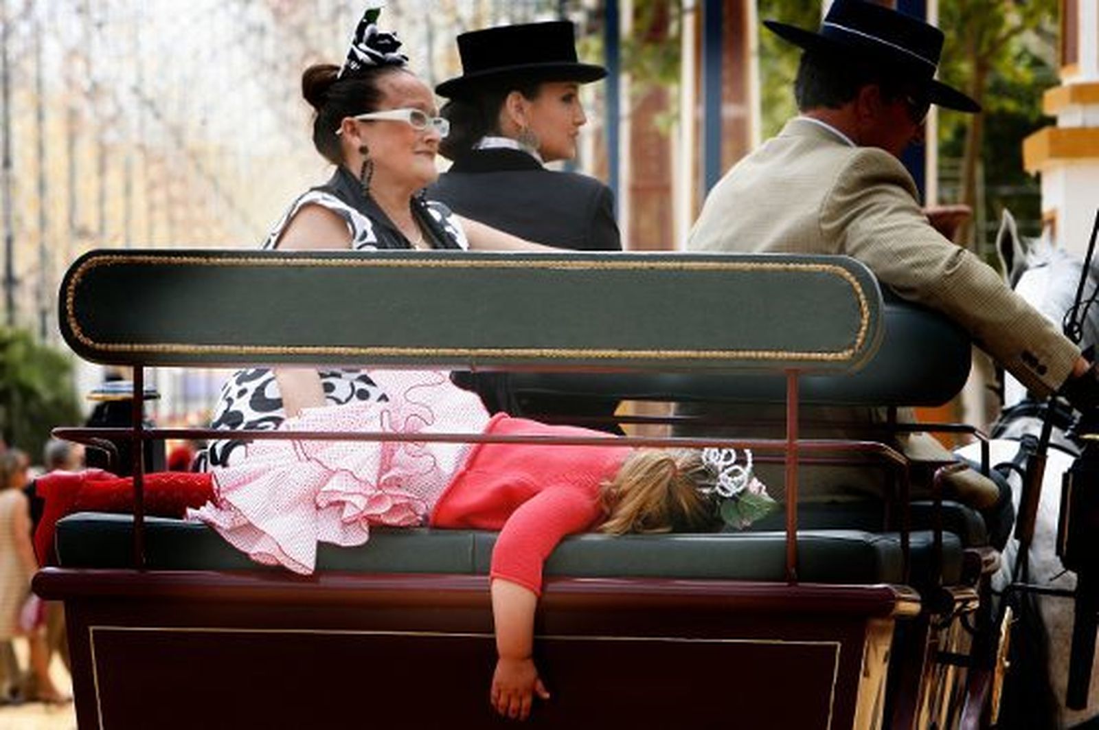 Una niña vestida de gitana, derrotada ya a estas alturas de la Feria, dormida en un enganche.   Foto: Pascual