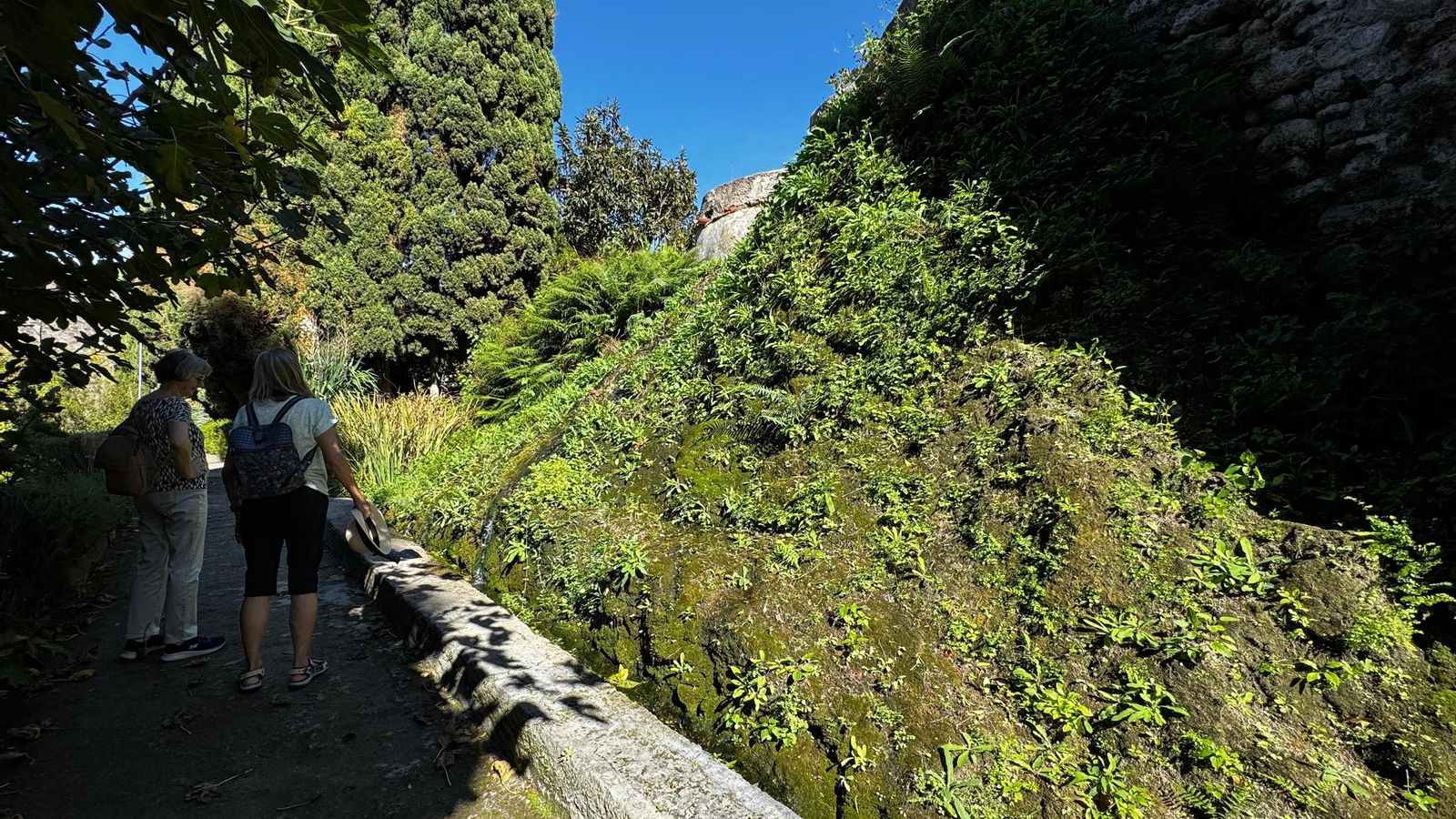 Dos personas observan el paso del agua por una de las acequias del Jardín Nazarí