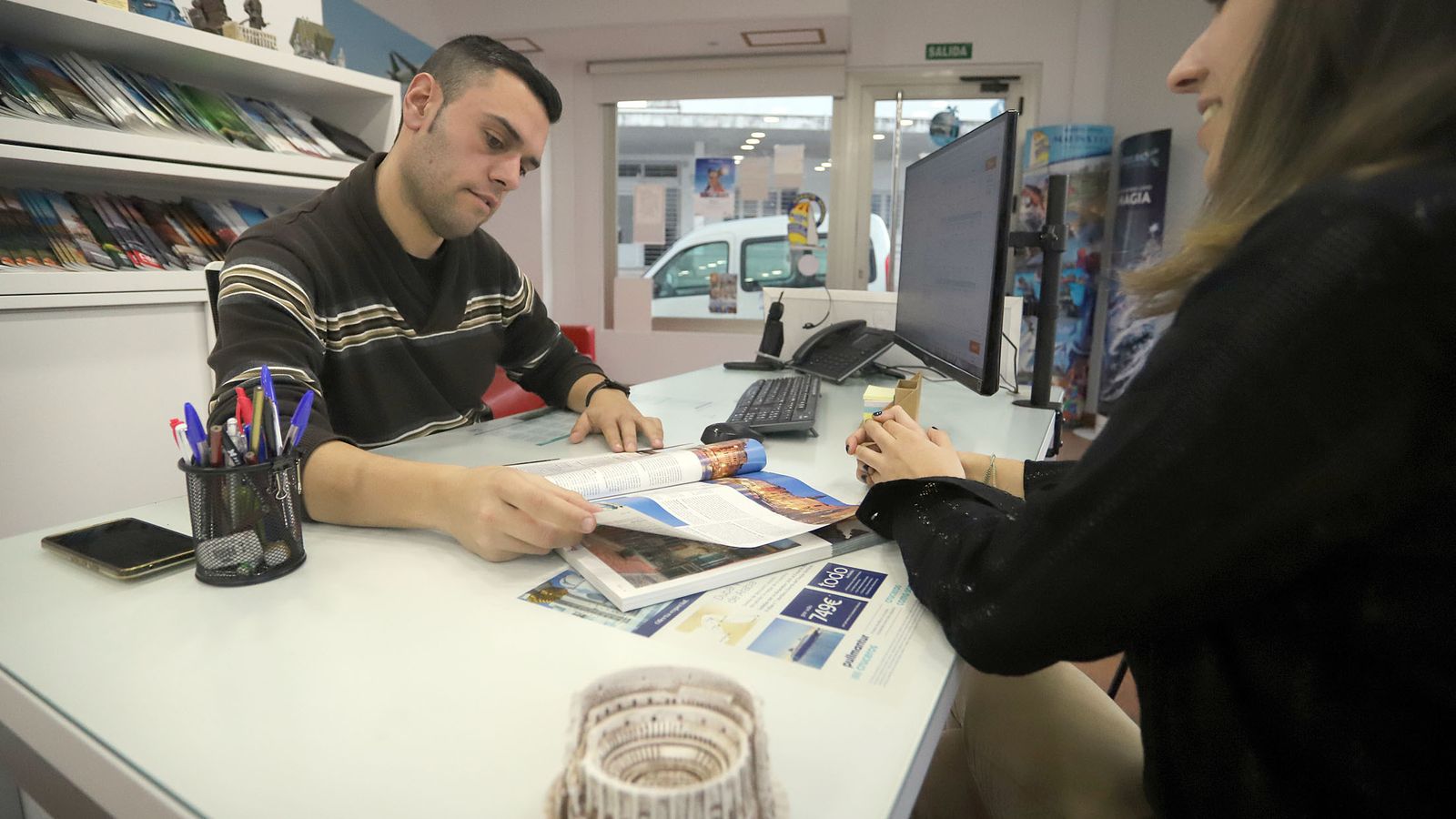 Una mujer pregunta por ofertas de viaje antes del confinamiento.