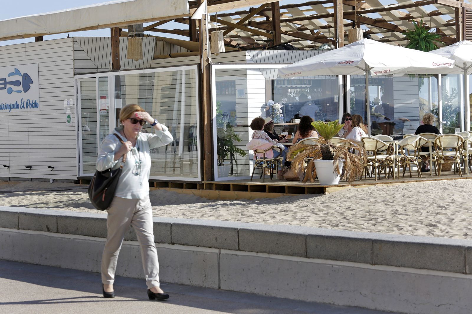 Una mujer pasea ante un chiringuito de La Victoria