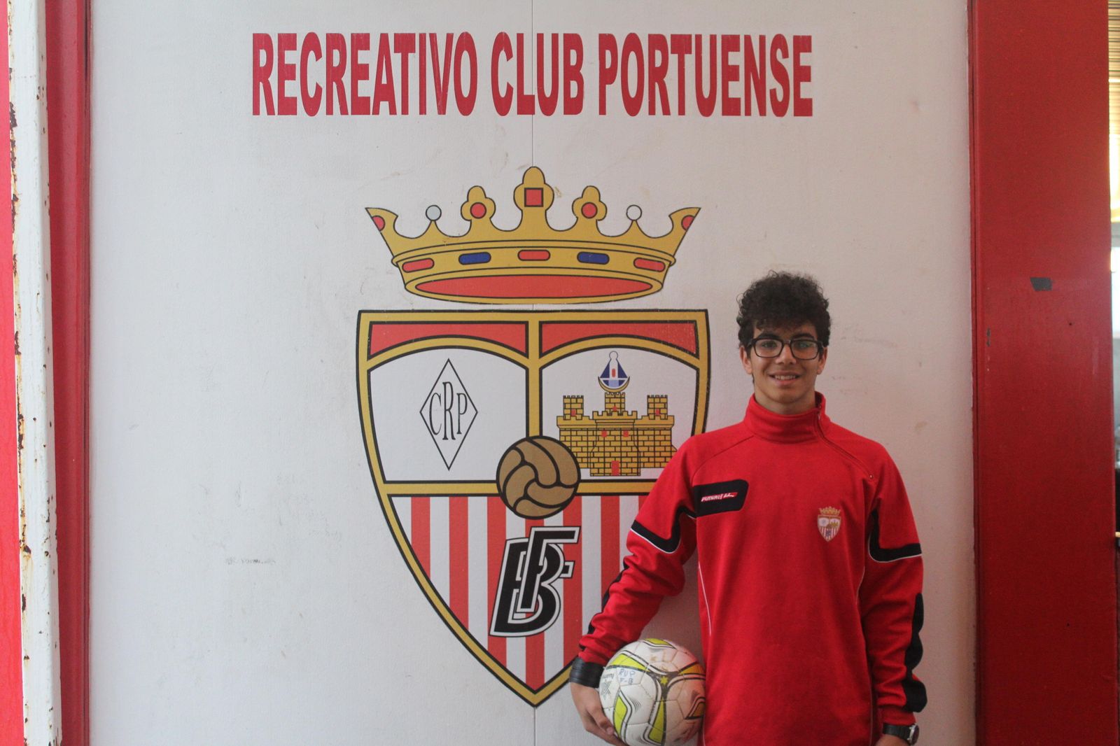 Adri López posa junto al escudo del Recreativo Portuense.