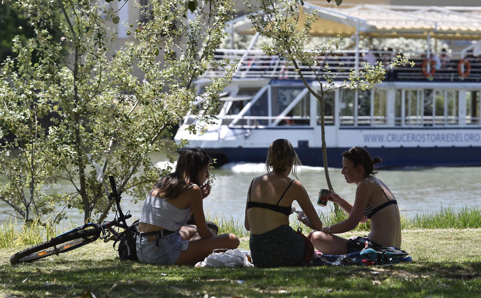 Tres jóvenes se refrescan a orillas del río.