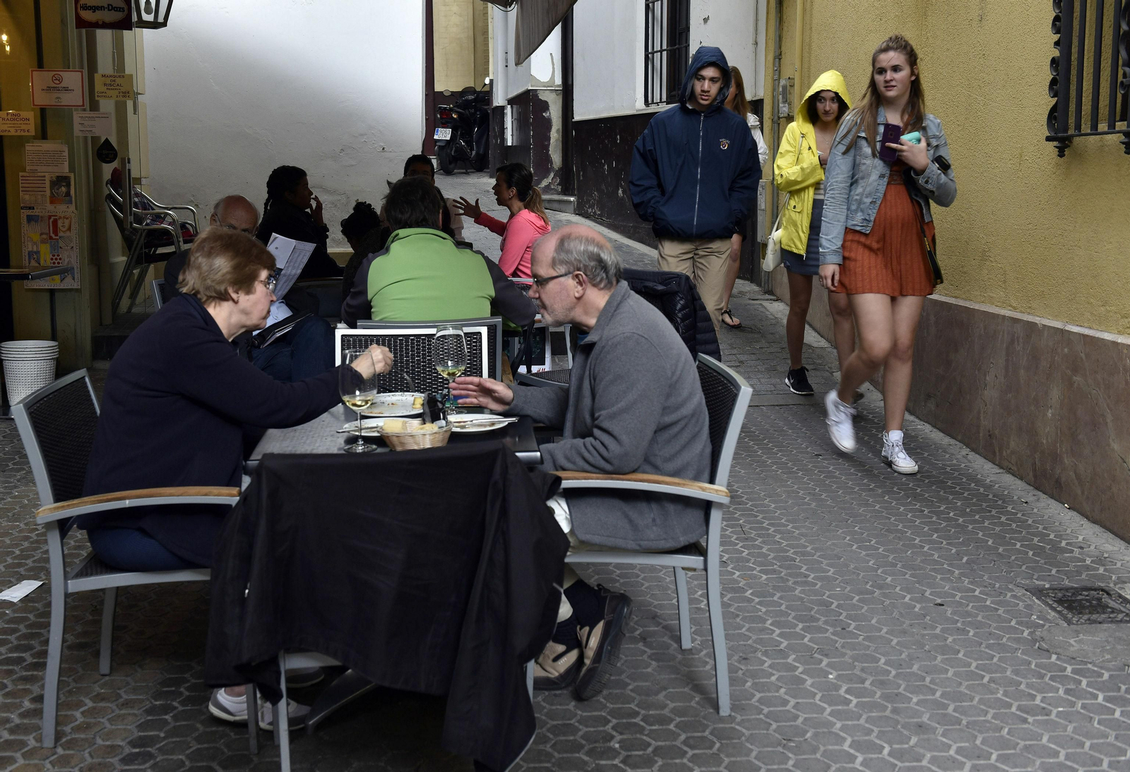 Veladores en una calle estrecha del barrio de Santa Cruz.