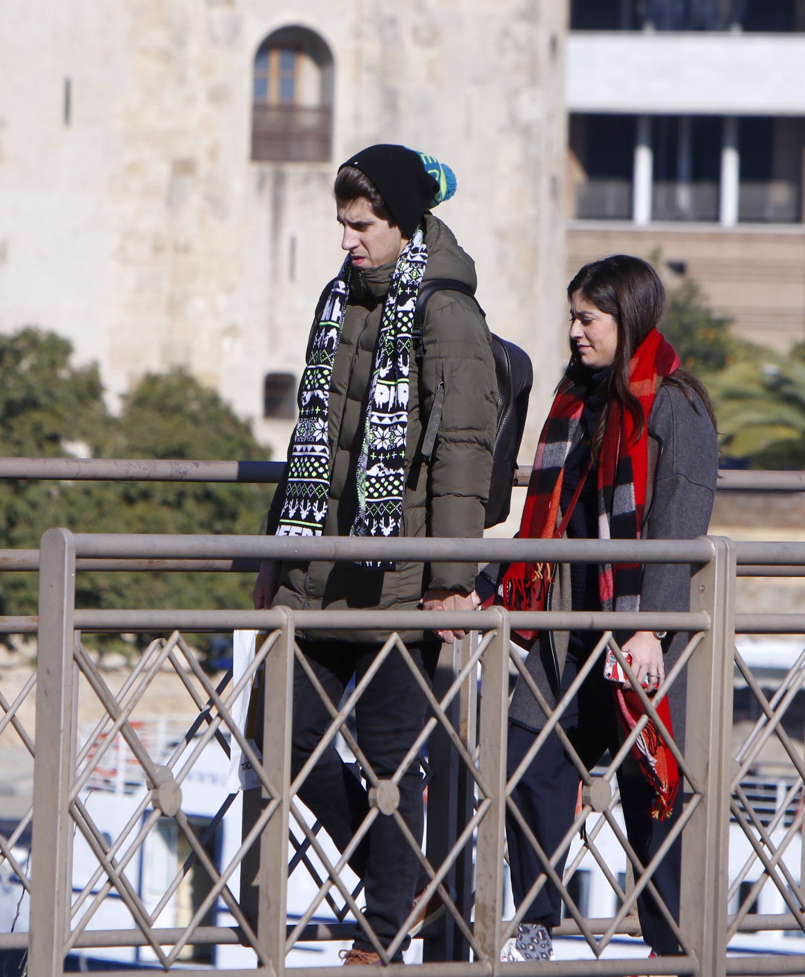 Una pareja pasea por Sevilla con abrigos, bufandas y gorros.