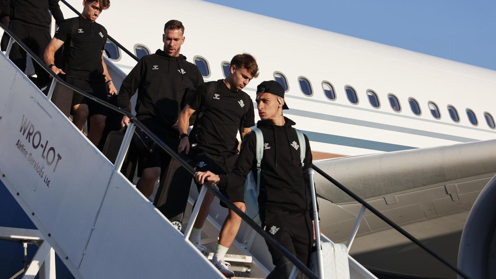 Antony encabeza un grupo de futbolistas bajando del avión en Breslavia con Adrián entre ellos.