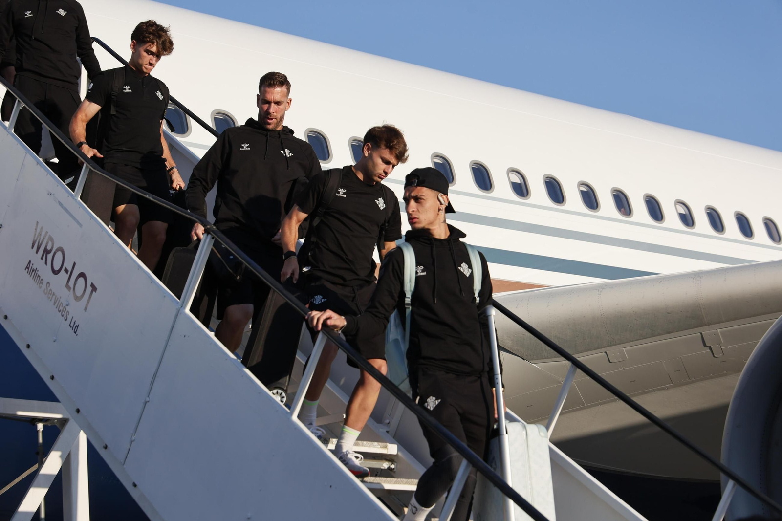 Antony encabeza un grupo de futbolistas bajando del avión en Breslavia con Adrián entre ellos.