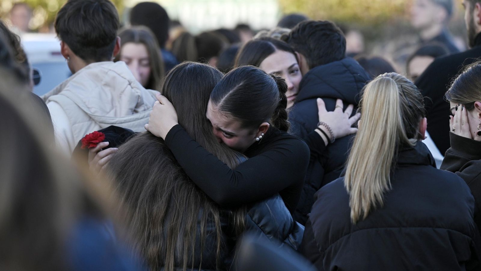 Varias personas de abrazan durante el funeral. Varias personas de abrazan durante el funeral.
