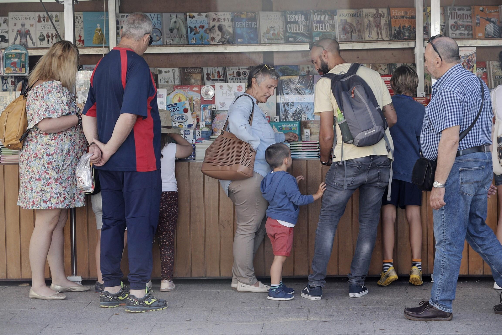 Uno de los expositores de la Feria del Libro con los primeros clientes, entre ellos algunos pequeños.