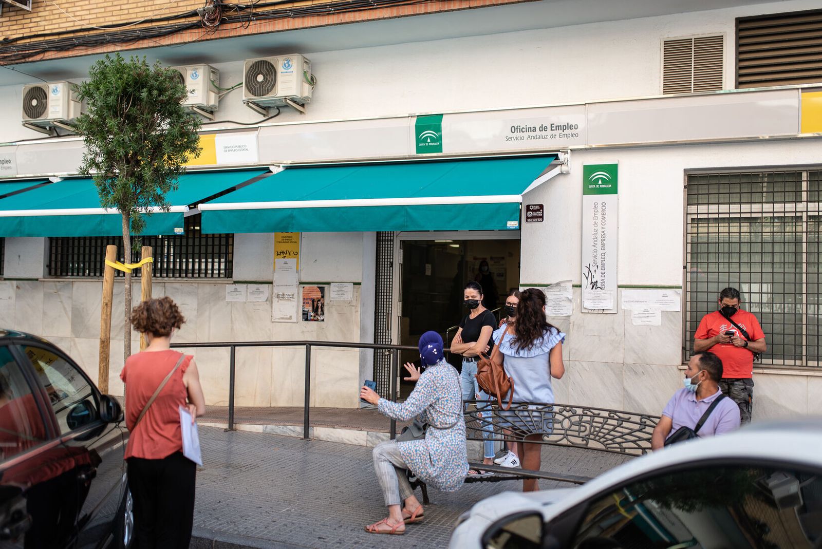 Varias personas esperan a las puertas de una oficina de empleo.
