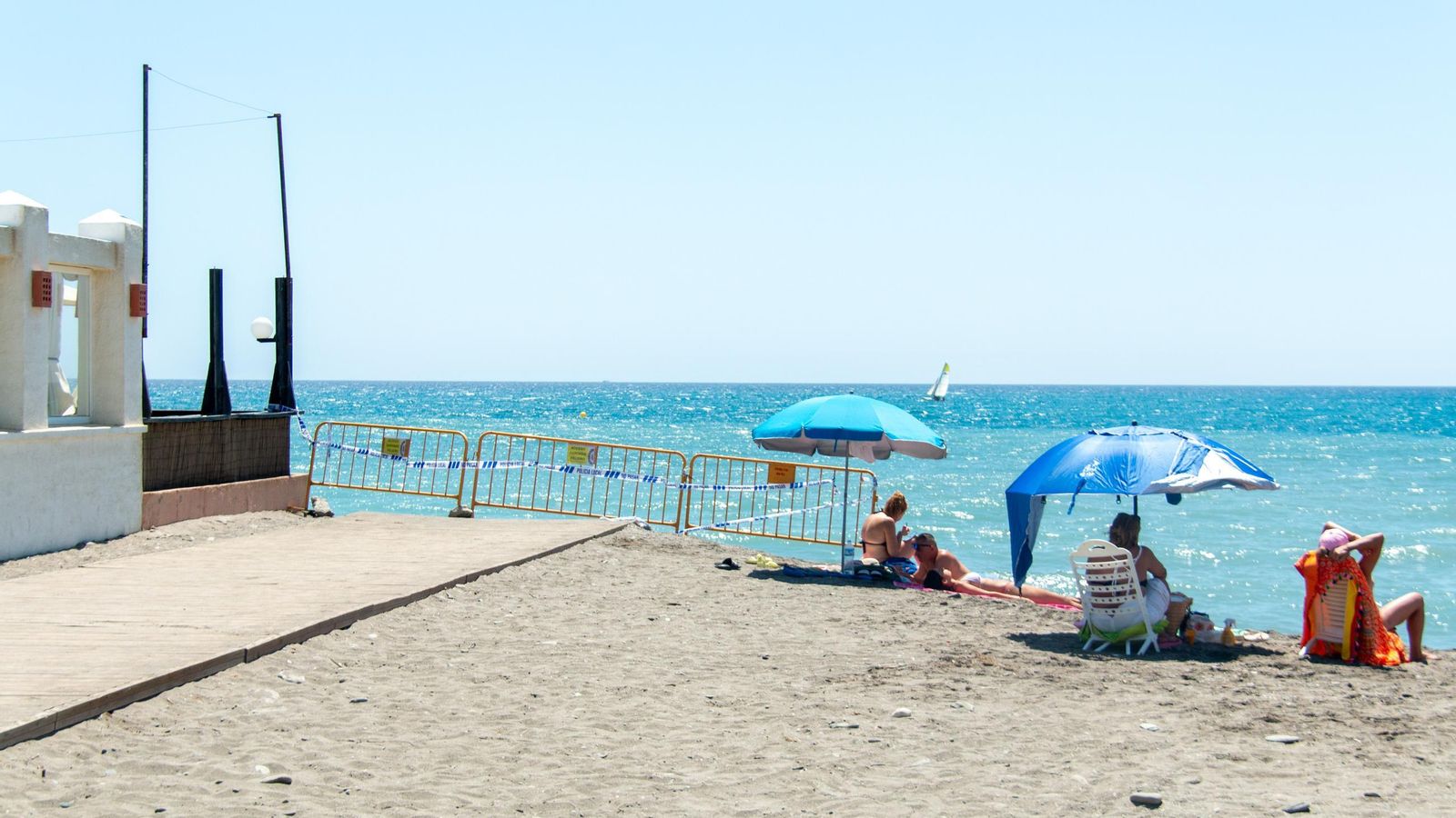 Varias personas disfrutan del día de playa junto a la zona acordonada