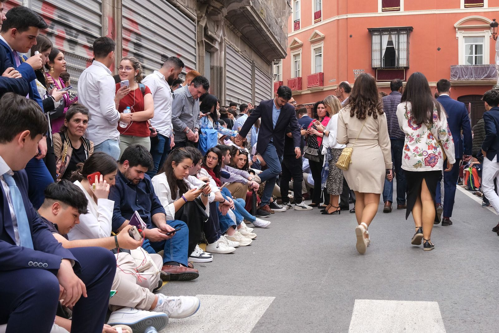 Público sentado en sillitas y en los bordillos de las aceras durante la Semana Santa.