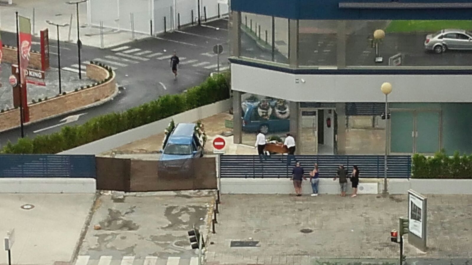 Operarios trasladan un ataúd a la vista del vecindario.