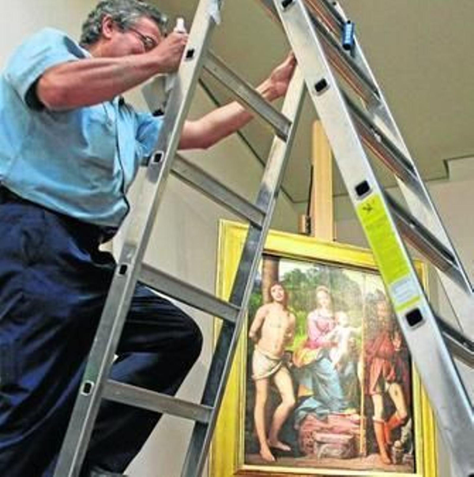 Un operario del museo ajusta un foco frente al cuadro 'Madonna con el niño' de Bernardino Luini.