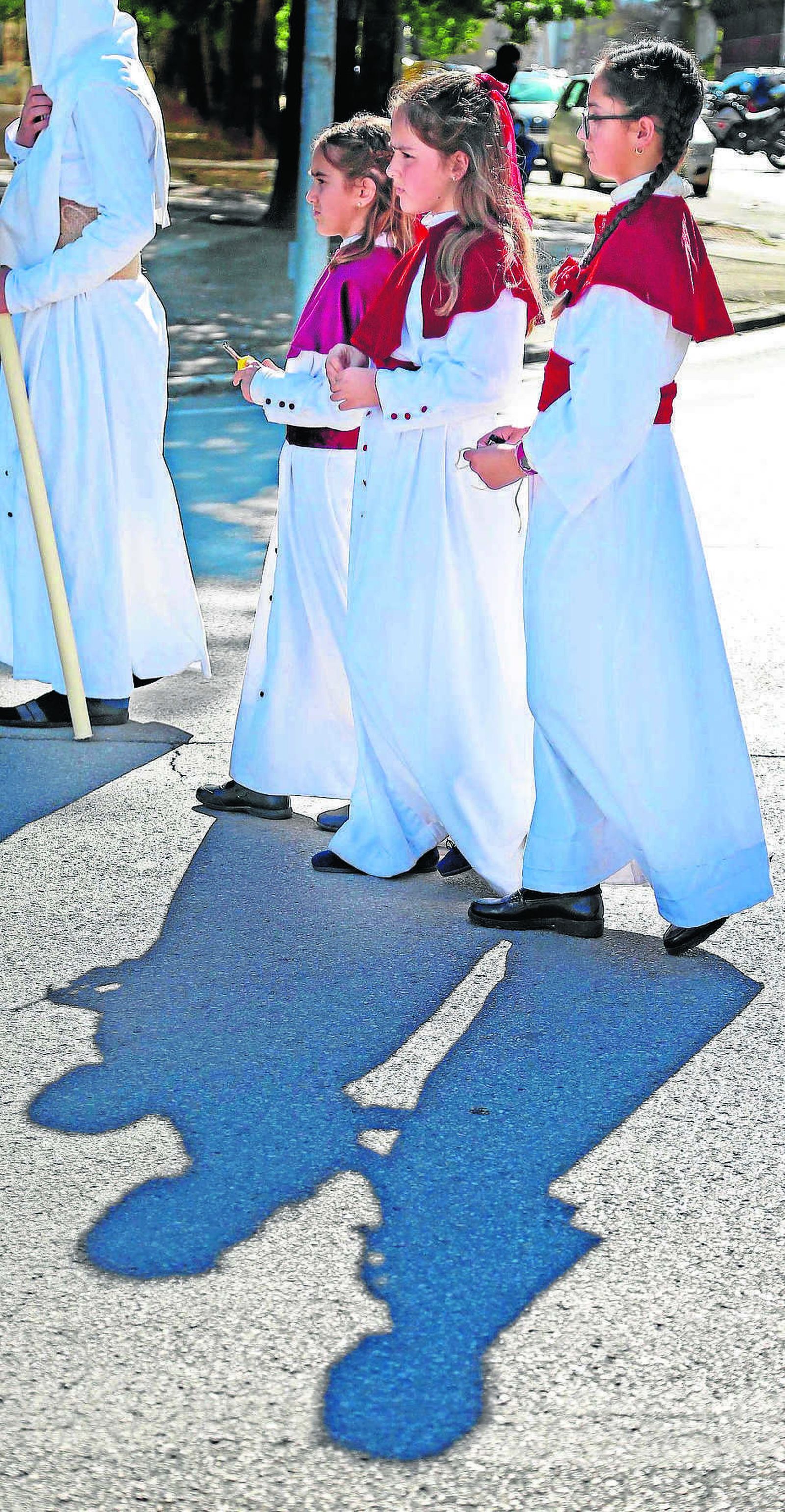 Tres monaguillas de la Hermandad de la Clemencia camino de la carrera oficial con los encendedores para ejercer su labor en las manos.