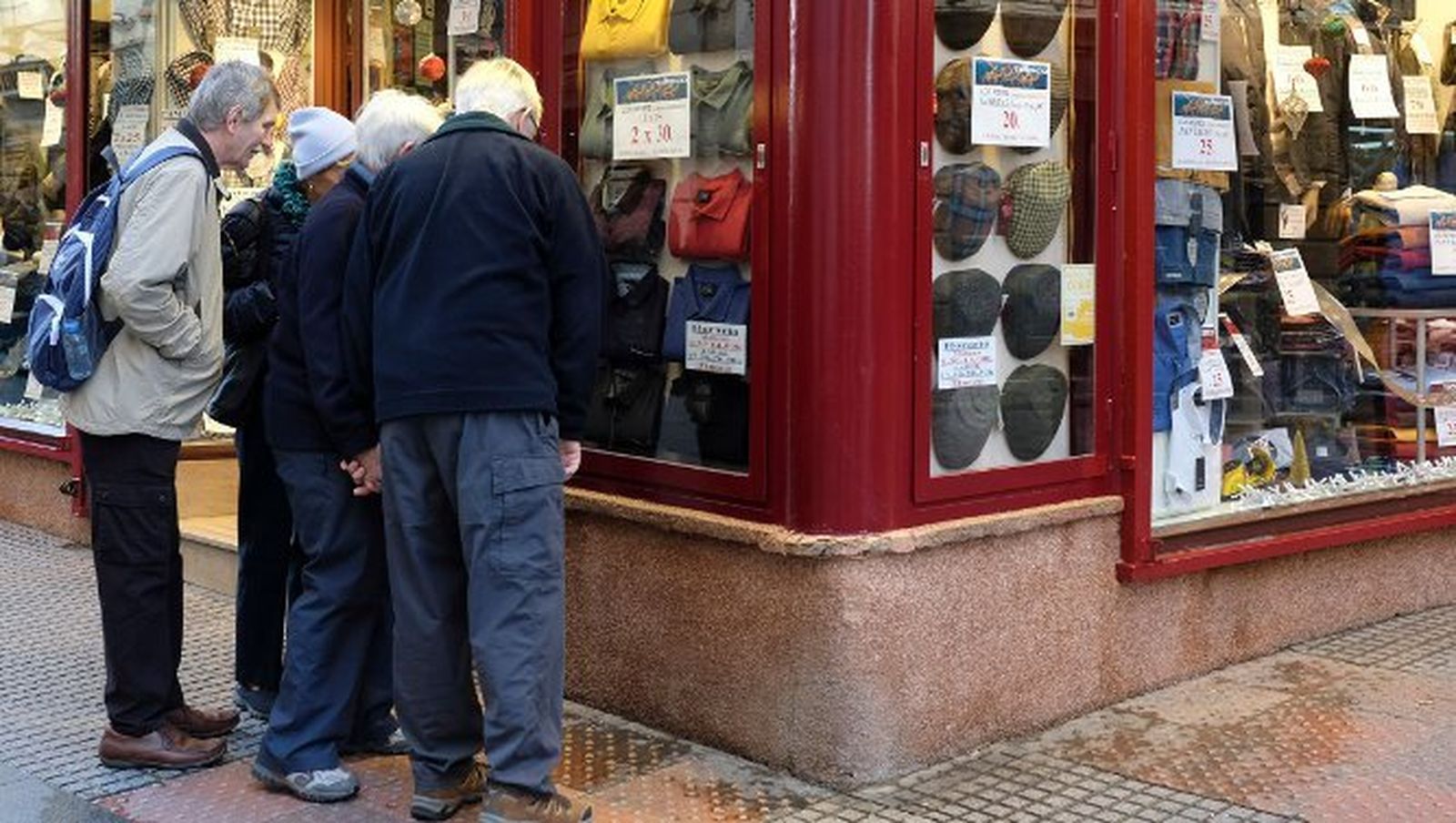 Unos turistas  miran los precios del escaparate de un negocio tradicional.