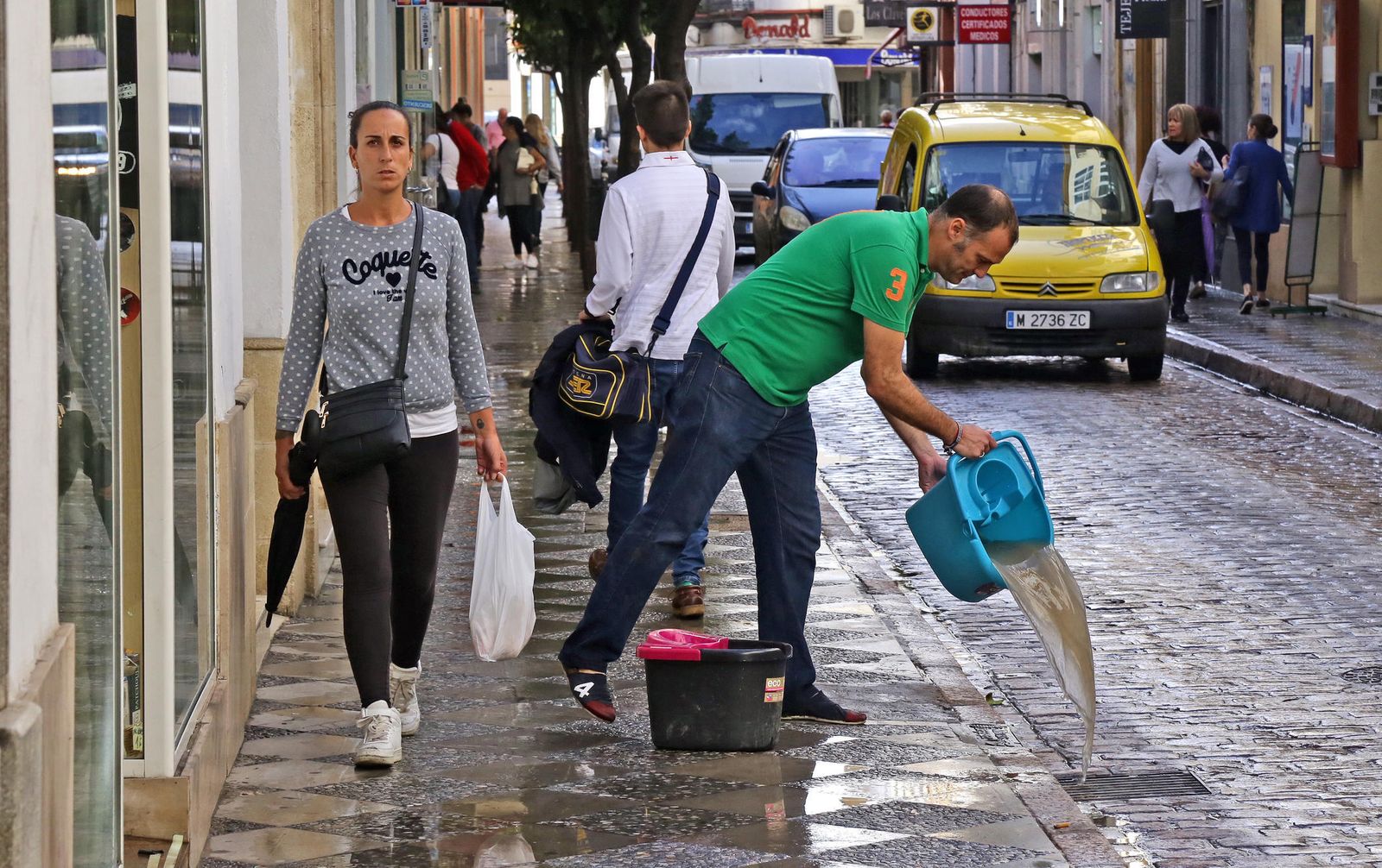 Un hombre achica agua de un comercio en calle Honda, una de las más afectadas por las inundaciones en el centro.