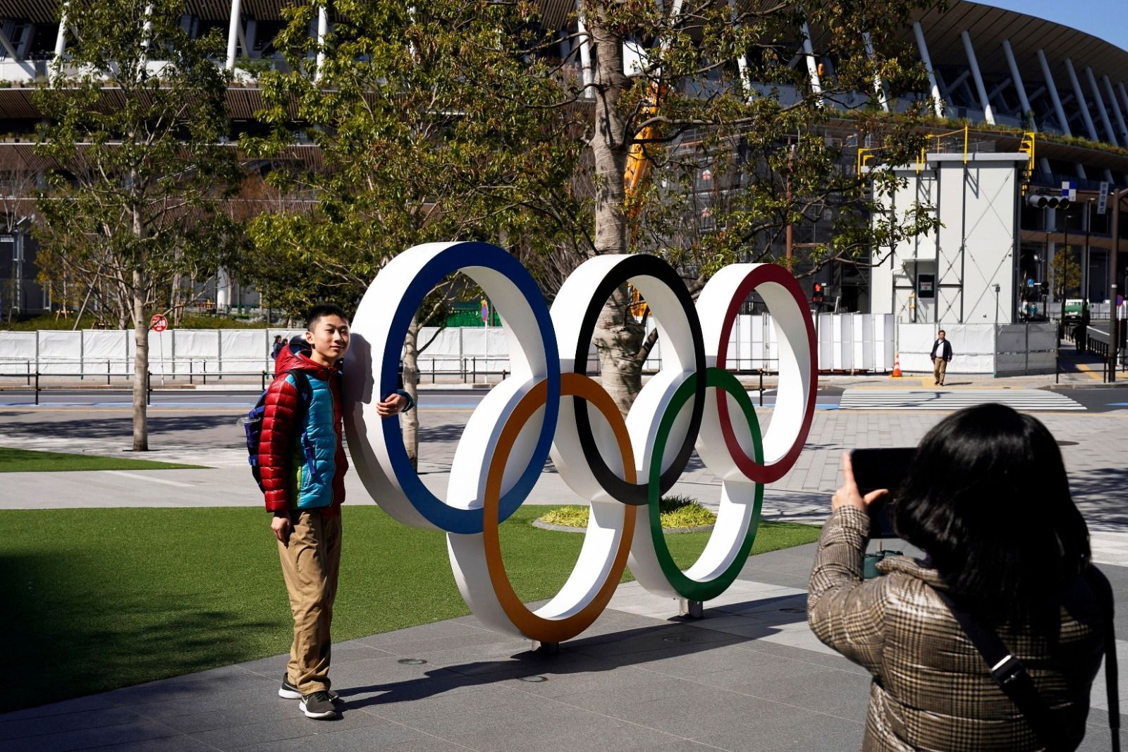 Un hombre posa junto a los aros olímpicos delante del estadio de Tokio.