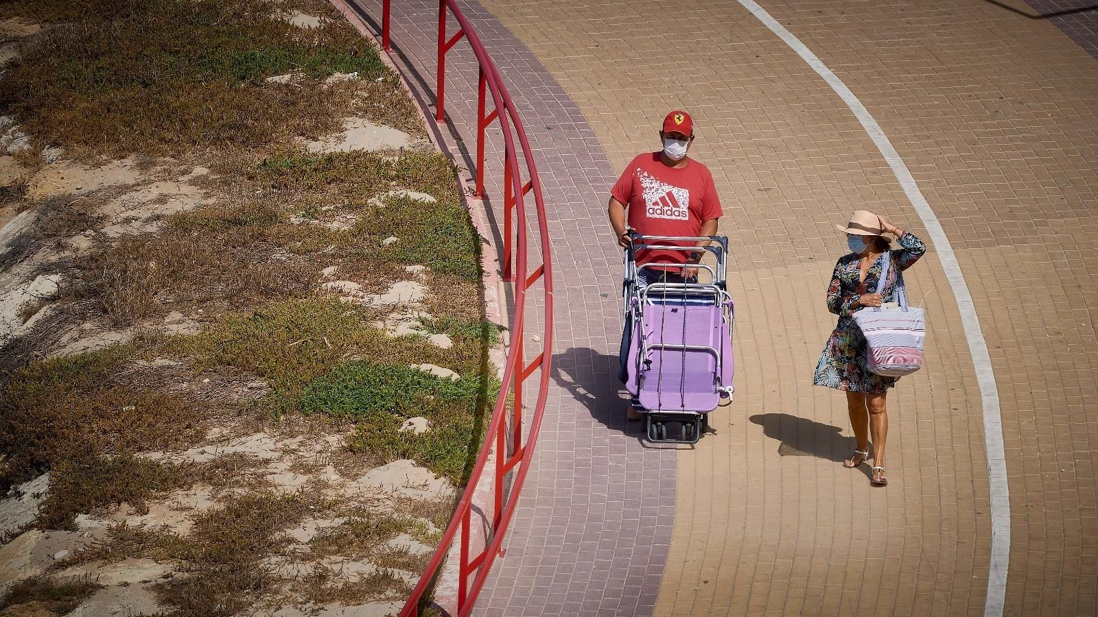 Personas llegando con mascarilla a la playa Santa María del Mar.