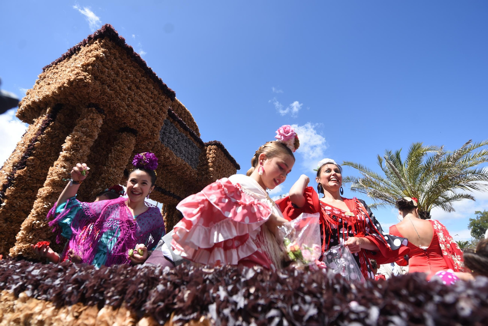 Varias chicas lanzan claveles desde una de las carrozas en la Batalla de las Flores de Córdoba.