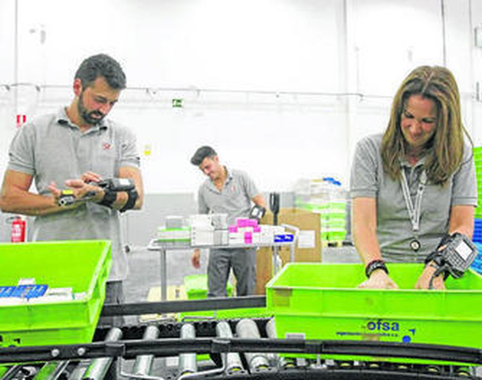 Dos trabajadores colocan productos en la cinta transportadora.