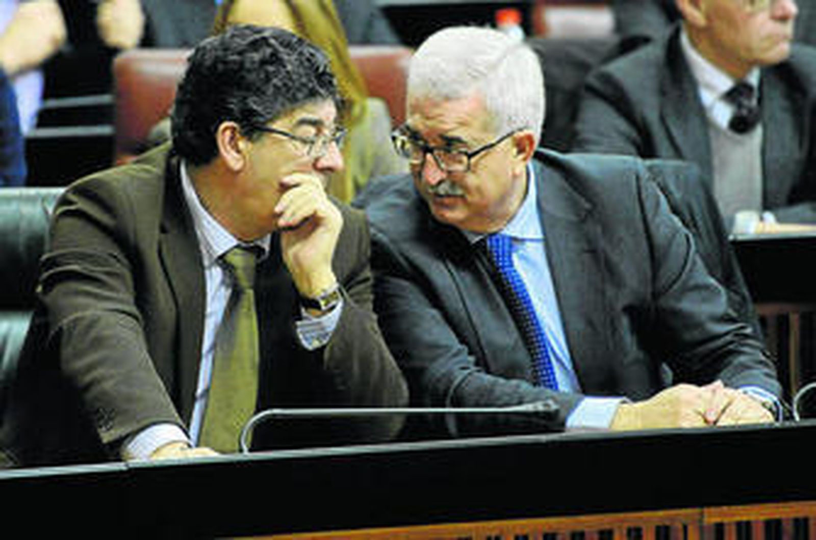 Diego Valderas conversa con Manuel Jiménez Barrios, consejero de la Presidencia, en un pleno en el Parlamento.