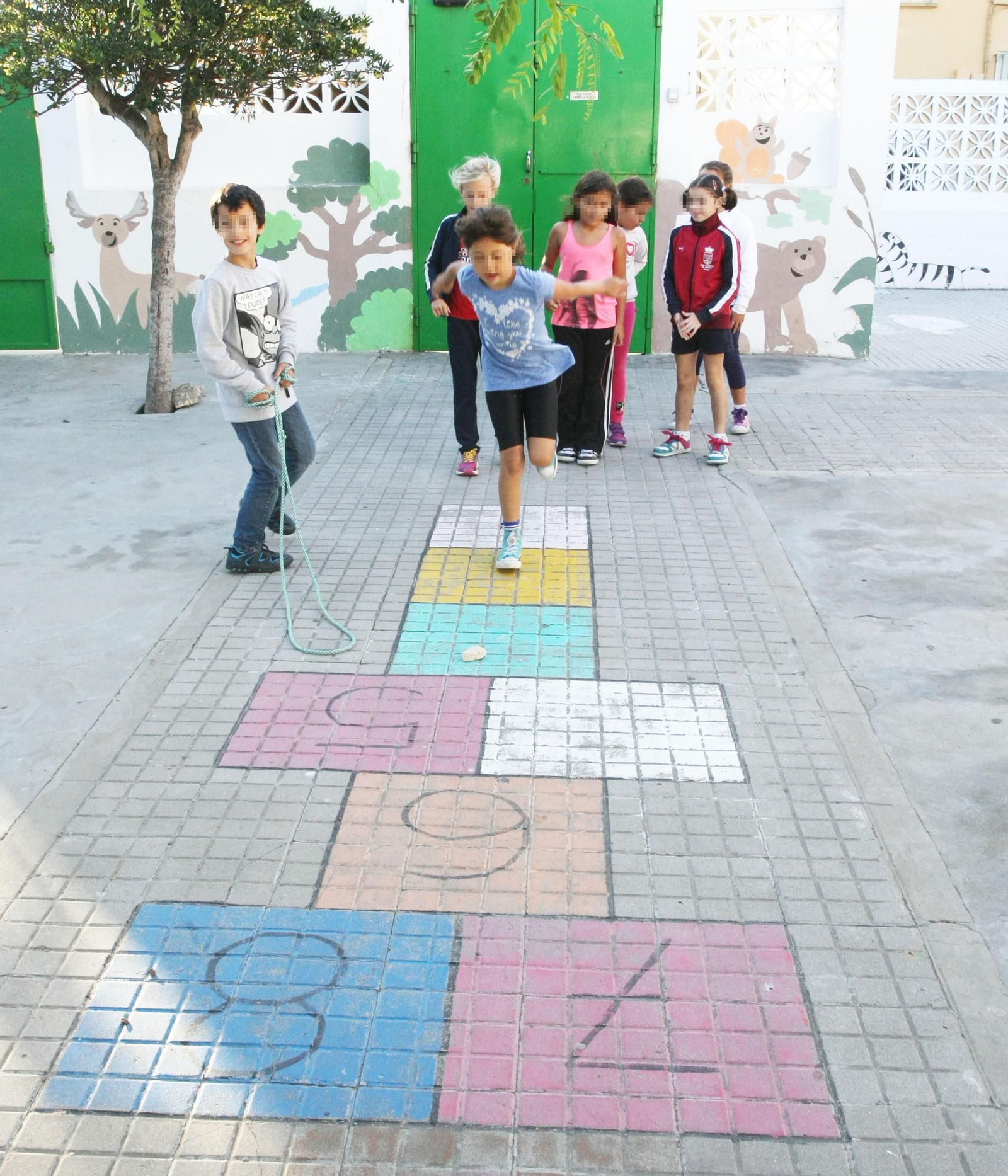 Niños jugando a la rayuela en un patio escolar.