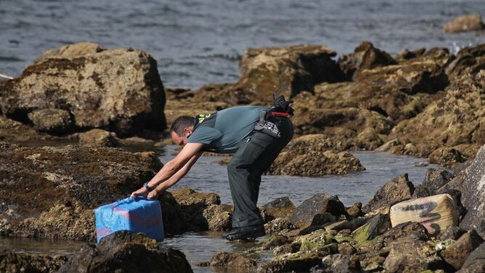 Un guardia civil rescatando un fardo de hachís varado en una imagen de archivo.