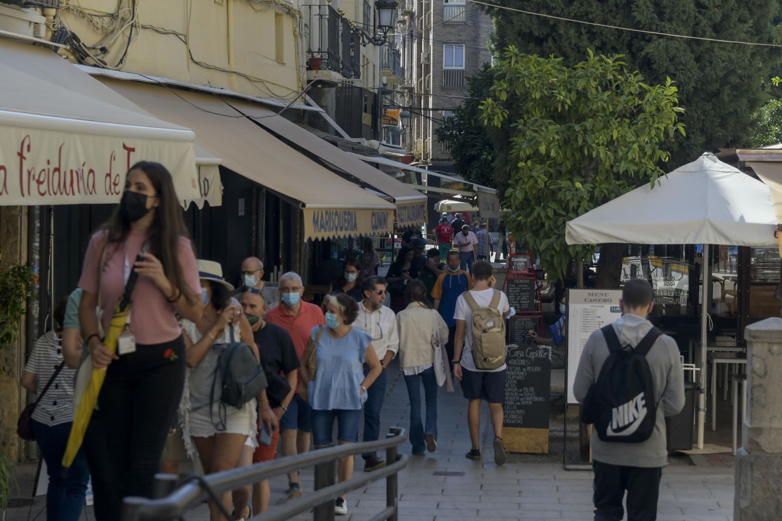 Personas con y sin mascarilla en una calle de Granada.