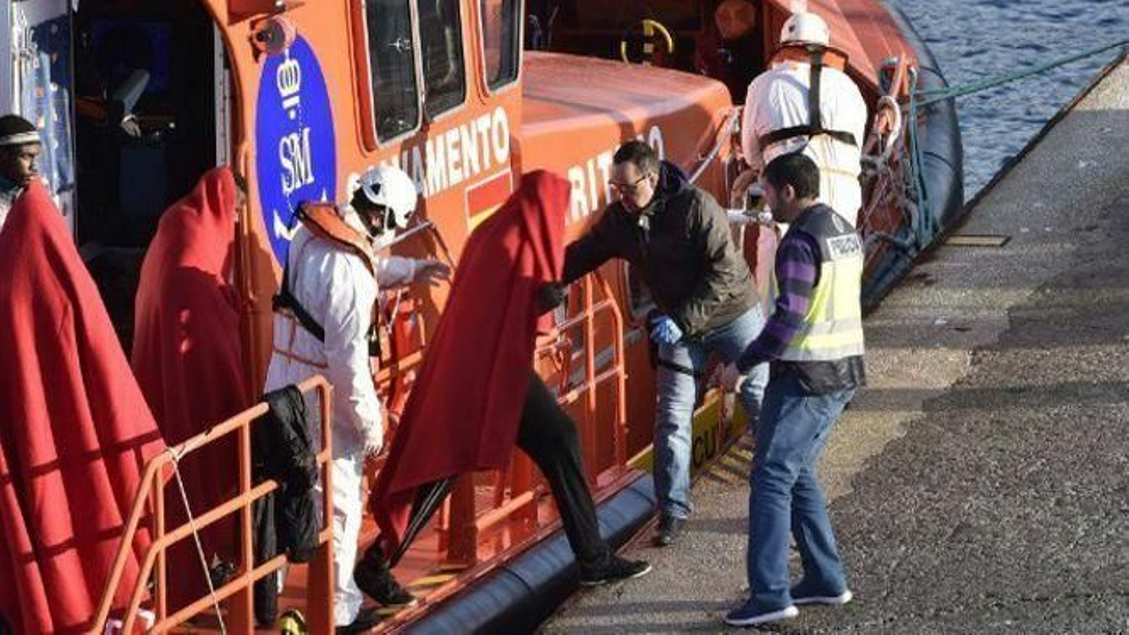 Un grupo de migrantes abandona una embarcación de Salvamento Marítimo.