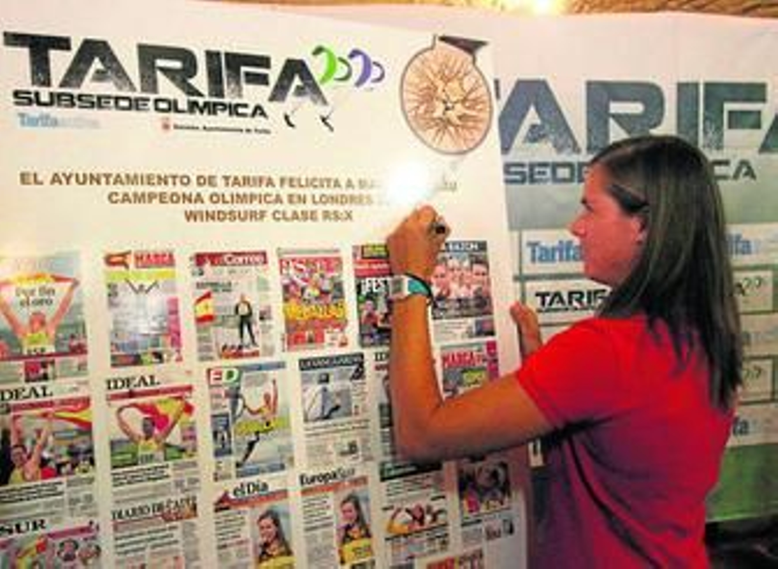 1. Marina Alabau deja una dedicatoria en uno de los muchos regalos que recibió, un cuadro con las portadas de periódicos con su victoria. 2. La campeona enseña su medalla de oro de la clase RS:X.  3. La sevillana firma en el libro de la ciudad ante la mirada de Gisela Pulido, la campeona del mundo de kitesurf criada en Tarifa, que arropó a Alabau y enterró la polémica que existe entre windsurf y kite. 4. Entre los muchos asistentes destacaron los padres de su primer entrenador, Kim Lithgoe, ya fallecido.  Reportaje gráfico: Fran Montes.