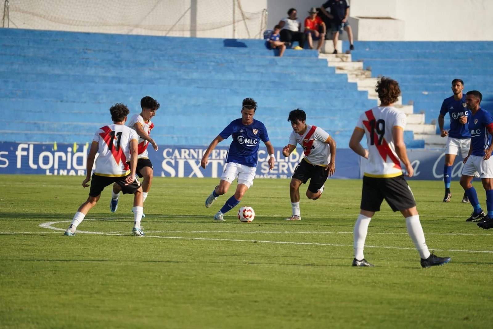 Rubén del Valle conduce el balón rodeado de jugadores del filial rayista.