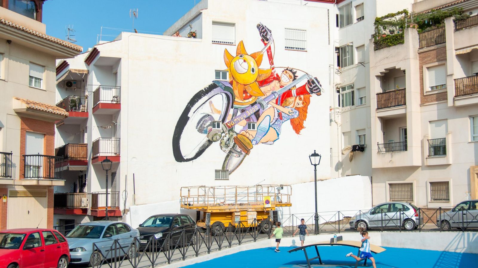 Varios niños juega en la plaza con el mural de fondo
