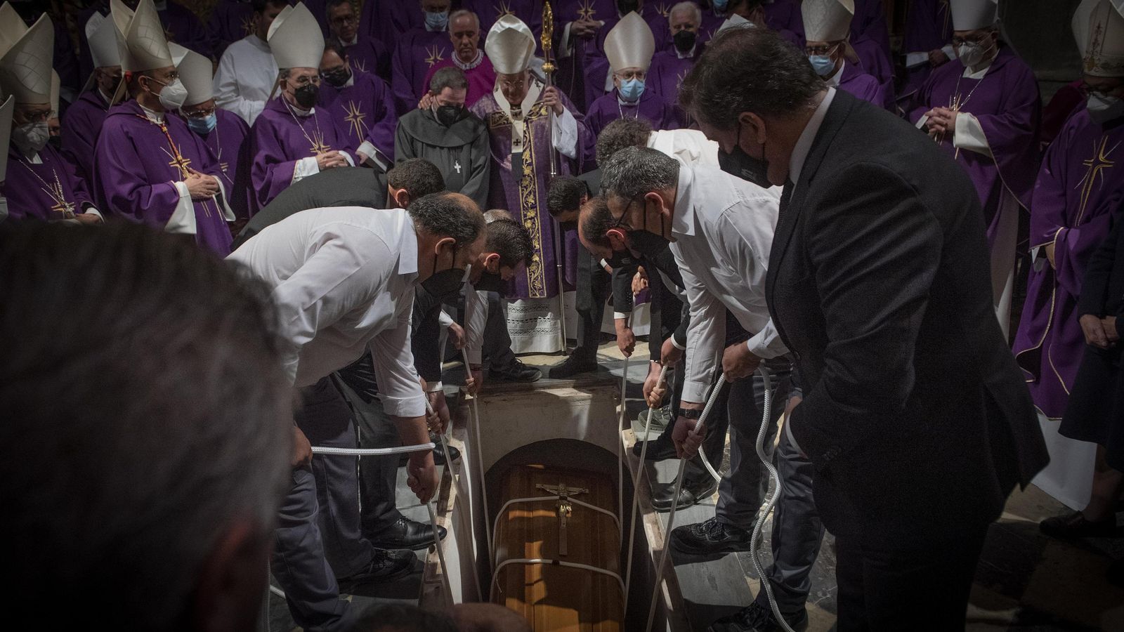Los operarios introducen el ataúd del cardenal Amigo en la tumba mientras el arzobispo abraza al hermano Pablo.