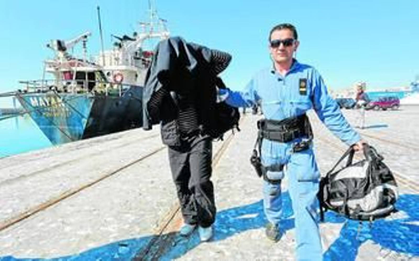 Un agente lleva a uno de los detenidos en la operación.