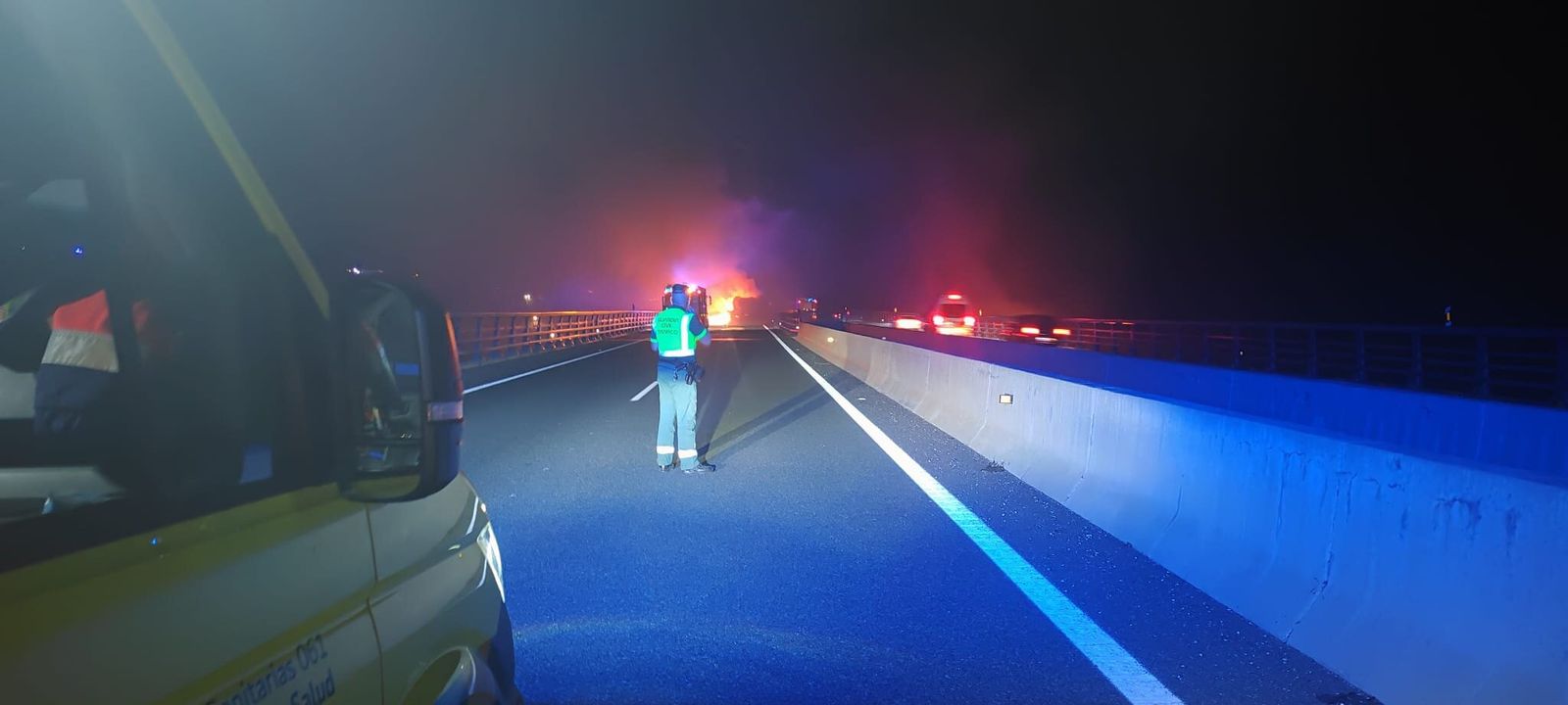 Un guardia civil vigila la A-7 con el camión aún ardiendo.
